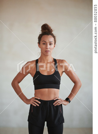 Vertical medium portrait of young adult Caucasian woman with muscular body wearing sports clothes looking at camera 88032855