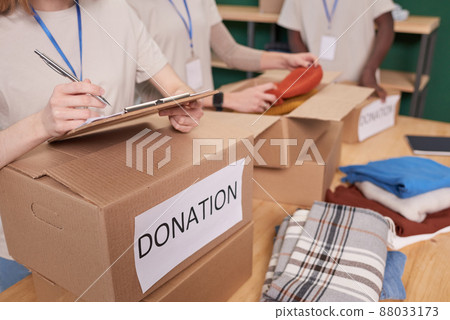 Group of unrecognizable young people volunteering in clothes charity checking and sorting out items 88033173