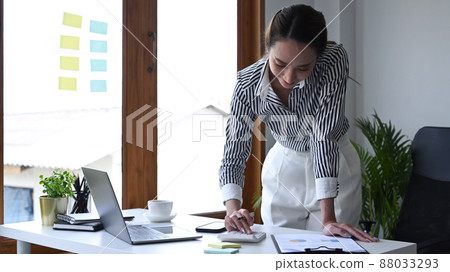 Female accountant standing and using calculator at office desk. Female accountant standing and using calculator at office desk. 88033293