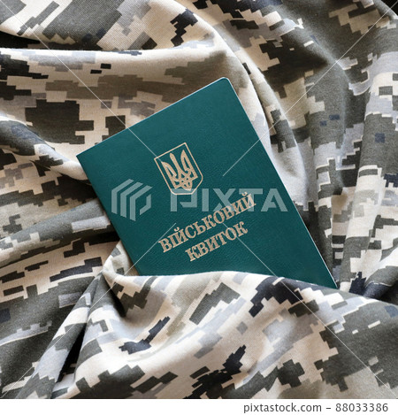 Ukrainian military ID on fabric with texture of pixeled camouflage. Cloth with camo pattern in grey, brown and green pixel shapes with Ukrainian army personal token 88033386