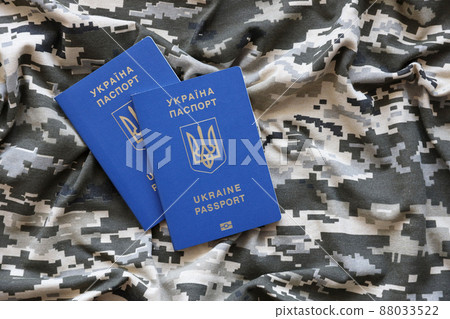 Ukrainian foreign passport on fabric with texture of military pixeled camouflage. Cloth with camo pattern in grey, brown and green pixel shapes and Ukrainian ID Ukrainian foreign passport on fabric with texture of military pixeled camouflage. Cloth with camo pattern in grey, brown and green pixel shapes and Ukrainian ID 88033522