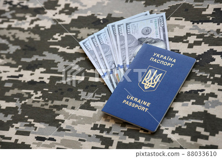 Ukrainian foreign passport on fabric with texture of military pixeled camouflage. Cloth with camo pattern in grey, brown and green pixel shapes and Ukrainian ID 88033610