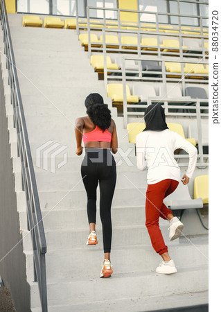Two black women running up a stairs on a stadium Two black women running up a stairs on a stadium 88034720