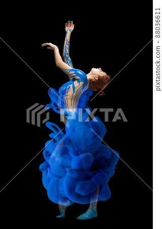 Portrait of young beautiful woman covered with black thick pain and dye splash dancing isolated over black background. Emotive dance Portrait of young beautiful woman covered with black thick pain and dye splash dancing isolated over black background. Emotive dance 88036611