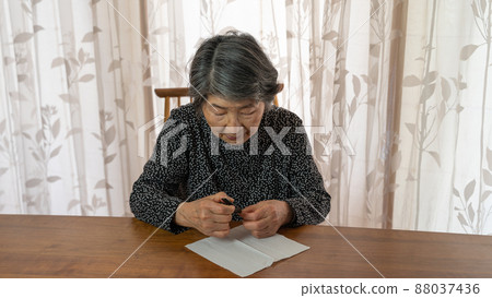 An elderly woman in black clothes cutting her fingernails with a nail clipper An elderly woman in black clothes cutting her fingernails with a nail clipper 88037436