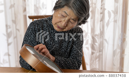 An elderly woman in black clothes resetting the hands of a clock that has stopped An elderly woman in black clothes resetting the hands of a clock that has stopped 88037438