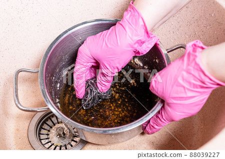 hands scrub stewpan with burnt food by sponge 88039227