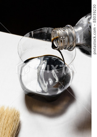 pouring wood stain from bottle into jar close up pouring wood stain from bottle into jar close up 88039230