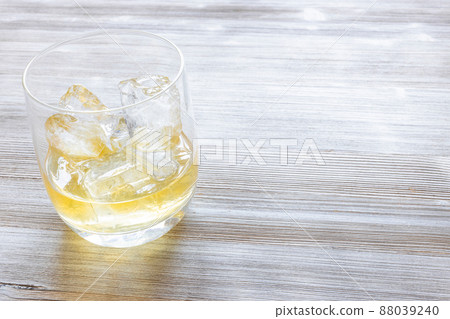 portion whisky on the rocks in glass on gray table portion whisky on the rocks in glass on gray table 88039240