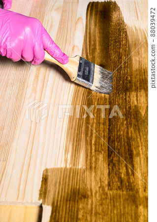 gloved hand covers wooden board with wood stain gloved hand covers wooden board with wood stain 88039472