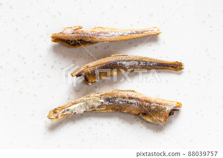 few dried anchovy fishes close up on gray few dried anchovy fishes close up on gray 88039757