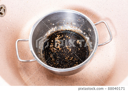 stewpan with burnt food in pink sink at home 88040171