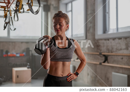 Sporty female athlete lifting kettlebell in gym Sporty female athlete lifting kettlebell in gym 88042163