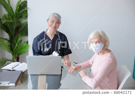 Female doctor examining patient at her home Female doctor examining patient at her home 88042171
