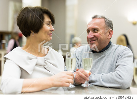 Mature man and woman drinking champagne in theater lobby Mature man and woman drinking champagne in theater lobby 88042422