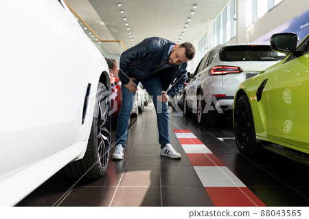 a man in a car dealership chooses new tires and alloy wheels for his car a man in a car dealership chooses new tires and alloy wheels for his car 88043565