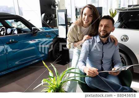 a married couple studying the terms of new car insurance at a car dealership. Concept of road safety 88043658