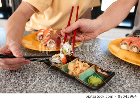 Lovely couple having fun while eating sushi rolls at home, croped shote, hands close up 88043964