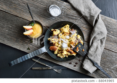 Traditional Viennese Kaiserschmarrnserved in an iron frying pan on old planks on a slate plate  88043965