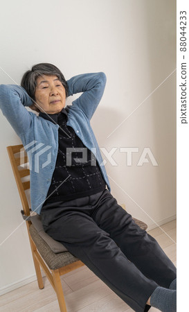 一位白髮老婦移動身體，雙手伸到腦後 88044233