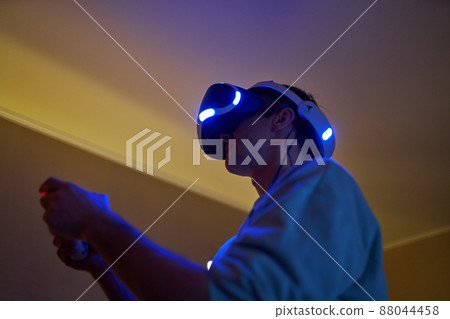 Man is playing gamepad while wearing VR goggles Man is playing gamepad while wearing VR goggles 88044458