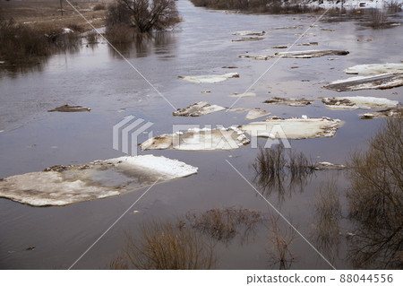Lined up in a row, small white ice floes float along the river. Lined up in a row, small white ice floes float along the river. 88044556