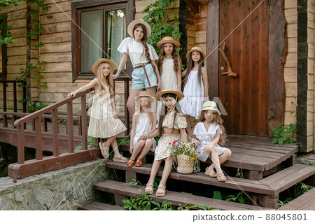 Tween girls posing together on doorstep of wooden country house in summer Tween girls posing together on doorstep of wooden country house in summer 88045801
