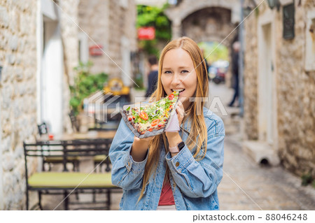 Young woman tourist eating traditional pizza in the old town of Budva. Travel to Montenegro concept Young woman tourist eating traditional pizza in the old town of Budva. Travel to Montenegro concept 88046248