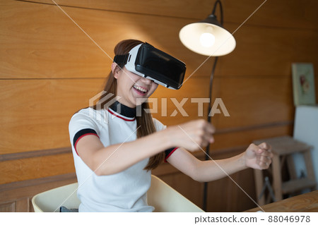 Excited young woman in VR goggles driving car in virtual reality. Lady screaming when turning virtual steering wheel, teen playing in racing computer game or road simulator. 88046978