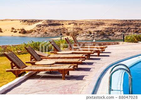 Row of swimming pool lounge chairs with the view of Nasser Lake at Abu Simbel Village. 88047028