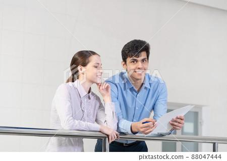 young woman and colleague discuss document young woman and colleague discuss document 88047444