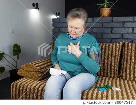 Senior woman measure blood pressure. Device for self-diagnosis and control of the heart. High or low pressure. Hypertension or hypotension. The concept of cardiovascular disease 88047517