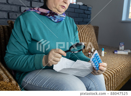 Senior woman reads instructions for medicines. Woman looks at the list and composition of the drug. Concept home self-medication and study of the properties of drugs. Contraindications. How to use 88047525