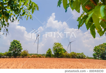 white windmill with blue sky and green environment, Single wind turbine to generate electricity for the benefit of the community, A large windmill stands in the middle of a field with a blue sky. 88048830