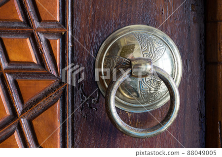 Closeup of antique copper ornate door knocker over an aged wooden door Closeup of antique copper ornate door knocker over an aged wooden door 88049005