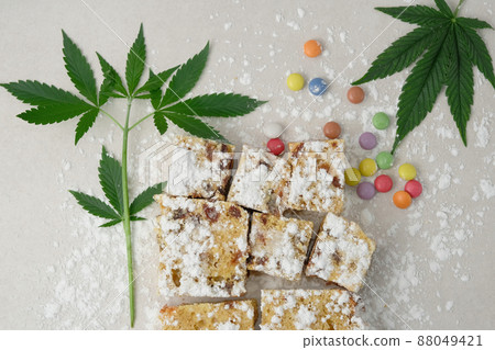 Craft cake with cannabis on light background. Layout with marijuana leaves Craft cake with cannabis on light background. Layout with marijuana leaves 88049421