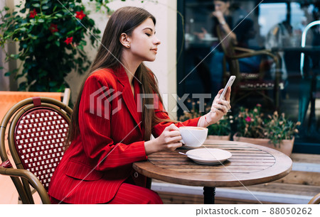 Young woman messaging on smartphone in cafe Young woman messaging on smartphone in cafe 88050262