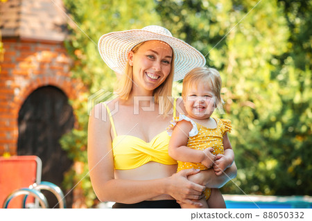 Summer vacation. Portrait of happy mother embracing her smiling little daughter. Swimming pool on the background. Summertime 88050332