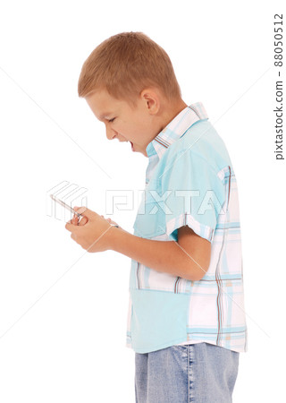 A young boy is furiously screaming into his cell phone. A young boy is furiously screaming into his cell phone. 88050512