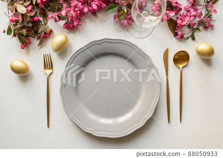 Easter festive dinner with golden eggs, festive tableware and flowers. 88050933