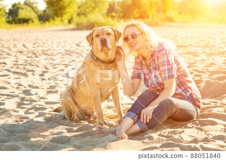 Young woman with her dog at the beach. Sun flare 88051840