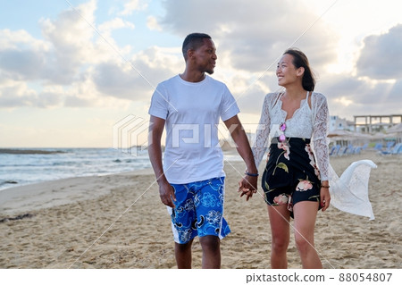 Young happy couple walking on the beach holding hands. 88054807