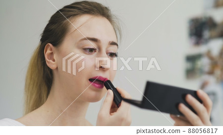 The girl paints her lips with lipstick. Close-up of the face. Macro photography of A Woman Wearing lipstick. The face macro. The girl looks in a small mirror The girl paints her lips with lipstick. Close-up of the face. Macro photography of A Woman Wearing lipstick. The face macro. The girl looks in a small mirror 88056817