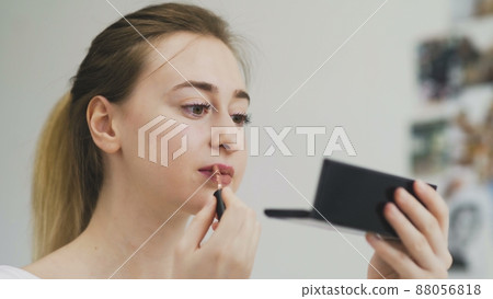 The girl paints her lips with lipstick. Close-up of the face. Macro photography of A Woman Wearing lipstick. The face macro. The girl looks in a small mirror The girl paints her lips with lipstick. Close-up of the face. Macro photography of A Woman Wearing lipstick. The face macro. The girl looks in a small mirror 88056818