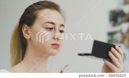 The girl paints her lips with lipstick. Close-up of the face. Macro photography of A Woman Wearing lipstick. The face macro. The girl looks in a small mirror The girl paints her lips with lipstick. Close-up of the face. Macro photography of A Woman Wearing lipstick. The face macro. The girl looks in a small mirror 88056820