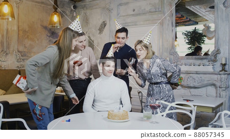 The birthday boy enjoys celebrating with his best friends by blowing out a cake candle and receiving gifts from friends. The birthday boy enjoys celebrating with his best friends by blowing out a cake candle and receiving gifts from friends. 88057345