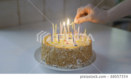 Hands lighting birthday cake candles. Closeup person hand light candle for celebration Hands lighting birthday cake candles. Closeup person hand light candle for celebration 88057354
