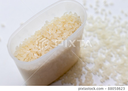 Plastic measuring cup and white rice grains 88058623
