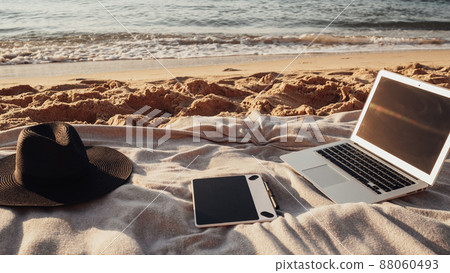 Close Up View of Laptop, Tablet and Hat Lying on the Plaid on Sandy Beach by the Sea, Freelance Concept, Remote Working 88060493