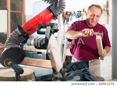 Worker performs measurements on wooden workpiece with caliper. Working with the measuring tool Worker performs measurements on wooden workpiece with caliper. Working with the measuring tool 88061478